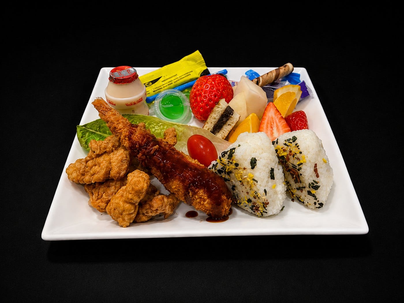 A children's set with fried chicken, a breaded prawn, rice balls and fruit