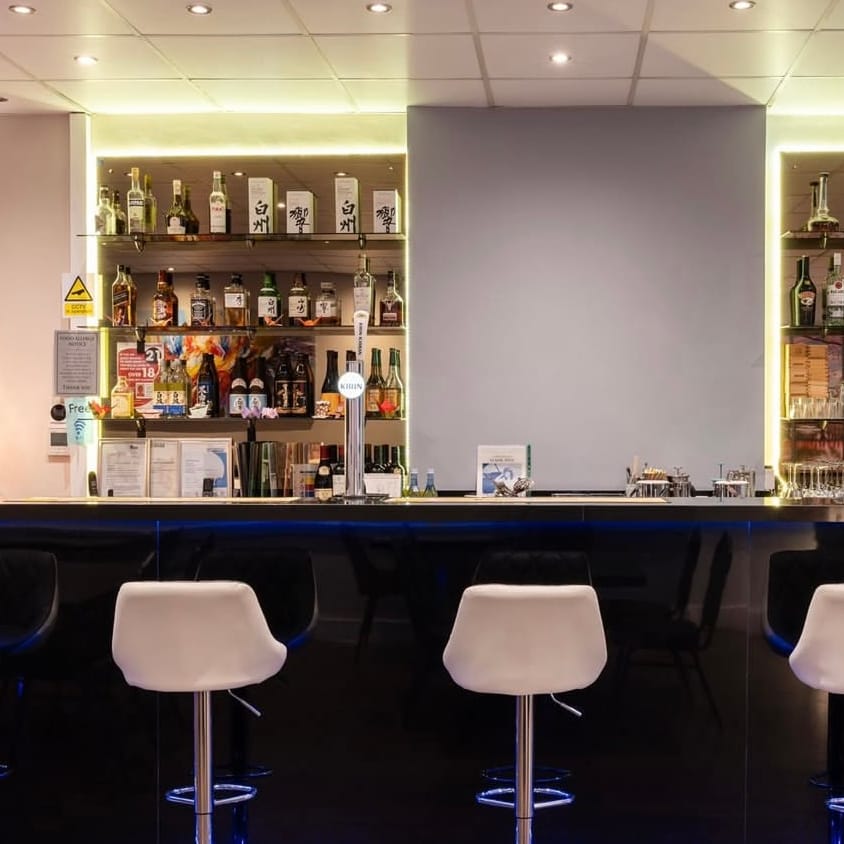 Back-lit shelves of sake and spirits behind the bar at Momo