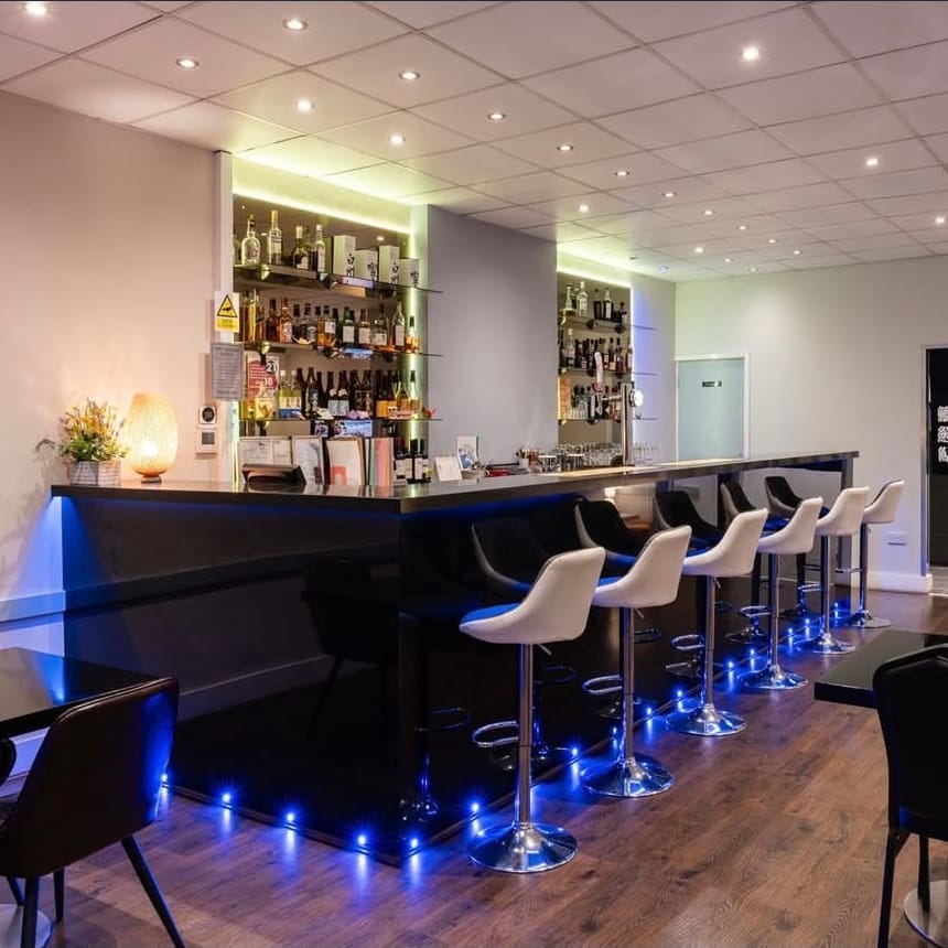 The bar and dining room at Momo, with white bar stools and black tables