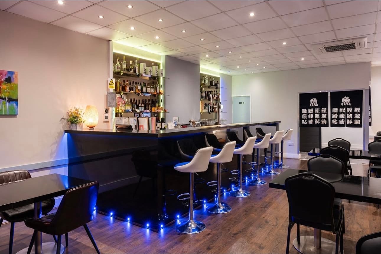 The bar and dining room at Momo, with white bar stools and black tables