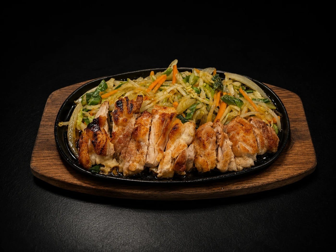 Chicken teriyaki on a sizzling iron plate with stir-fried vegetables