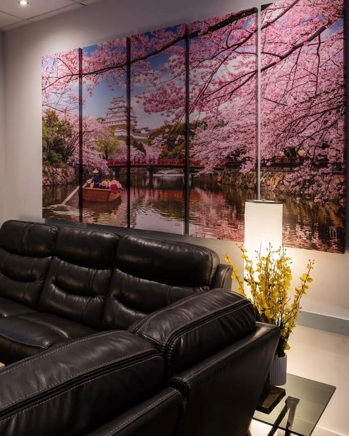 Lounge seating at Momo: black leather sofas beneath a cherry-blossom wall picture